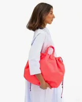 Bandolera grande de nylon reciclado color coral neón, con cierre de cordón ajustable y correa larga regulable.