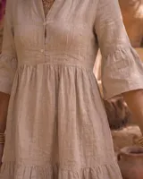 Vestido corto verde militar de lino, con cuello mao, escote en V con botones, mangas tres cuartos acampanadas con volados y falda con volado en el ruedo.