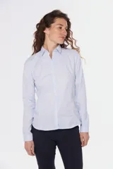 Camisa de tejido Oxford lisa y color blanco, con cuello camisero, cierre frontal de botones y mangas largas con puños abotonados.