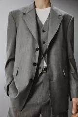 Blazer de corte regular confeccionada en tejido con lana, color gris. Presenta cuello con solapas de muesca, manga larga, bolsillos de vivo en el pecho y bolsillos de solapa en la cadera. Cuenta con cierre frontal de botones y aberturas en la espalda.
