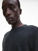 Sweater gris oscuro de lana merino 100% certificada, con cuello redondo y logo de Calvin Klein bordado en el pecho.