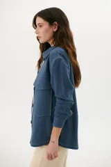 Sobrecamisa azul con cuello clásico, cierre frontal con botones y bolsillos de parche en el pecho.