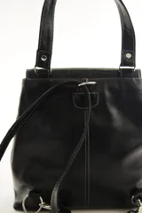 Mochila de cuero vacuno marrón con acabado pulido, solapa en forma de V y costuras decorativas. Cuenta con cremalleras laterales y asas ajustables.