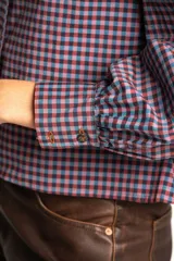 Camisa a cuadros azul y rosa con cuello babero, mangas largas abullonadas y cierre frontal con botones.