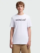 Remera de algodón blanca de corte clásico, con cuello redondo y mangas cortas. Presenta el nombre de la marca estampado en el frente en color negro, acompañado por el logo icónico de la marca en pequeño.