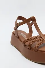 Sandalia de plataforma color marrón con tiras trenzadas y pulsera con hebilla.