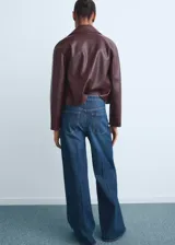 Jeans wide leg de tiro alto en color azul clásico, con diseño de cinco bolsillos, trabillas para cinturón y cierre frontal con cremallera y botón.