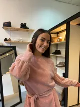 Vestido corto de lurex color salmón con brillo, escote redondo y mangas largas abullonadas. Incluye lazo para marcar la cintura.