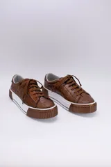 Zapatillas bajas color dorado con diseño trenzado, cordones y suela de goma.