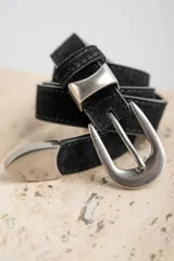 Cinto de cuero negro con textura de gamuza, presenta una hebilla metálica plateada de diseño clásico y puntera metálica a juego.