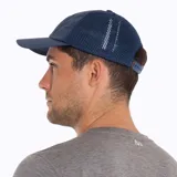 Gorra tipo trucker color azul, con panel frontal y visera de tela técnica, y paneles laterales y traseros de malla transpirable. Presenta un parche circular bordado en el frente con el logo de Merrell y un diseño de montaña.