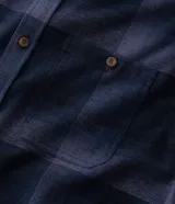 Camisa de franela a cuadros en tonos de azul marino y gris oscuro, con corte regular, manga larga, cuello camisero, cierre frontal de botones y un bolsillo en el pecho.