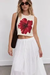 Top blanco de corte crop con gran estampado frontal de una flor roja estilo hibisco y cuello redondo.