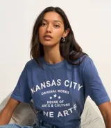 Remera azul de algodón con cuello redondo y mangas cortas. Estampado frontal con la leyenda "Kansas City Original Works House of Arts & Culture Fine Arts" en letras blancas.