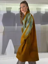 Tapado largo de fieltro de lana merino con teñido artesanal tie-dye en degradé de azul. Tiene cuello alto, cierre lateral con broches ocultos, bolsillos laterales y corte amplio.