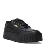 Championes Puma modelo Karmen II Idol, color negro con detalles dorados. Diseño de plataforma con parte superior de cuero y plantilla SoftFoam+ para mayor amortiguación.