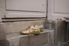 Championes de cuero negro con suela de caucho y cordones negros, con detalles de tachas metálicas en los laterales.