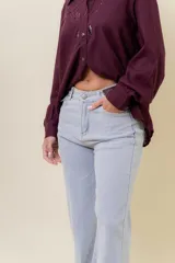 Pantalón de jean estilo wide leg, color celeste claro, con tiro medio, cinco bolsillos y cierre frontal con botón y cremallera.