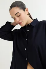 Camisa color crudo, de corte clásico, con cuello camisero, cierre frontal con botones y mangas 3/4 con trabillas.