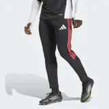 Pantalón de entrenamiento Adidas Tiro 26 Competition, de corte ajustado y color negro con las icónicas tres tiras laterales en color rojo. Presenta un diseño con textura en la parte inferior de las piernas y el logo de la marca en el muslo.