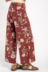Jean de corte wide leg con tiro medio, confeccionado en algodón peinado. Presenta un diseño estampado con motivos florales sobre una base de color bordó.