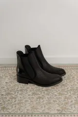 Botinetas de cuero color marrón con diseño tipo chelsea, con paneles laterales elásticos y detalle de cuero texturizado con acabado metalizado en el talón. Poseen taco bajo cuadrado y terminación redondeada.