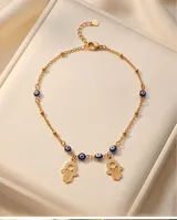 Tobillera de acero con baño de oro, con diseño de dijes colgantes de manos de Fátima (Hamsa) y cuentas intercaladas con detalles de ojos turcos azules.