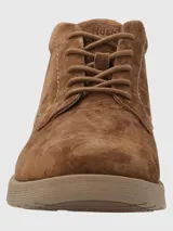 Bota de caña baja Hush Puppies, confeccionada en cuero gamuzado color marrón chocolate, con cierre de cordones al tono y suela de poliuretano con tecnología Spinal para mayor amortiguación y estabilidad.