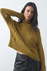 Polera de tejido de punto con diseño tramado y textura en relieve, cuello alto y mangas largas. Presenta un calce cómodo y holgado con terminaciones acanaladas en puños y ruedo.