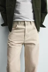 Pantalón jeans de corte recto y tiro medio, confeccionado en denim de algodón color beige con efecto lavado, bolsillos clásicos y cierre frontal con cremallera y botón.