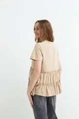 Remera de algodón color verde militar con cuello redondo, mangas cortas y detalle de volados fruncidos en la parte inferior.