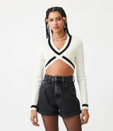 Suéter cropped de punto texturizado color crema, con escote en V y detalles a contraste en negro en mangas, cuello y busto.