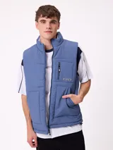 Chaleco acolchado reversible de nylon, color azul, con cierre frontal, cuello alto y bolsillos laterales. Presenta un bolsillo con cierre en el pecho y etiqueta de la marca.