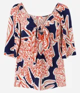 Blusa azul marino con estampado floral en tonos rojo y blanco, escote en pico con nudo y mangas cortas fruncidas.