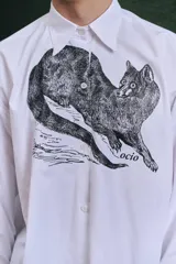 Camisa blanca de algodón con cuello clásico, manga larga con puños abotonados y estampado frontal de un animal similar a un zorro.