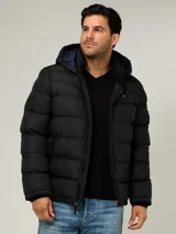 Campera puffer Tommy Hilfiger de color negro, acolchada con diseño horizontal, capucha integrada y cierre frontal de cremallera. Cuenta con bolsillos laterales con cierre y el logo bordado en el pecho.