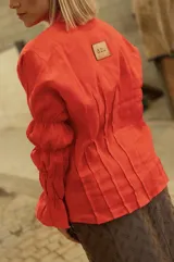 Camisa de lino color marrón con cierre frontal de botones, mangas largas con detalle de frunces y puños acampanados.