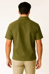 Camisa de lino color verde militar, de corte holgado, con cuello tipo solapa, botones frontales y manga corta.