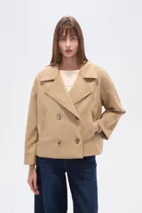 Chaqueta corta estilo peacoat, color beige, con cuello solapa y cierre cruzado de doble botonadura. Presenta un calce holgado y bolsillos laterales.