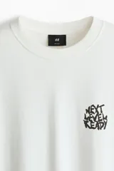 Remera de algodón blanca de corte holgado, con cuello redondo y un pequeño estampado gráfico negro en el pecho con el texto "NEXT LEVEL READY".