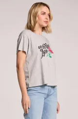 Remera gris melange de corte holgado, manga corta y cuello redondo, con estampa frontal que incluye la frase 'On the Road Again', el nombre 'Willie Nelson' y una rosa roja con tallo verde.