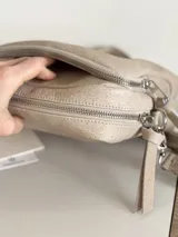 Bandolera color arena con correa de cuero y correa de tela intercambiables.