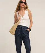Pantalón baggy de jean azul oscuro, de tiro alto con cintura elástica fruncida y lazo para ajuste. Presenta bolsillos laterales y dobladillos con vuelta en los tobillos.