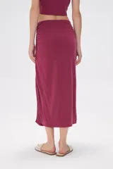 Falda midi de corte tubo confeccionada en modal, con detalle de frunces laterales que aportan movimiento y ajuste al cuerpo.