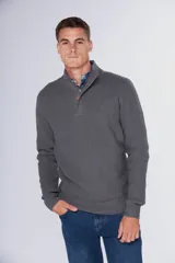 Buzo de tejido grueso color gris, con cuello alto y cierre frontal parcial. Presenta puños y ruedo acanalados, con un diseño de textura tejida en toda la prenda.