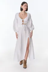 Vestido midi fucsia de lino, con escote en V, mangas largas abullonadas, lazos frontales y tajo lateral.