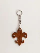 Llavero con dije en forma de flor de lis confeccionado en cuero color marrón, decorado con pequeños cristales incrustados y cadena metálica con argolla.
