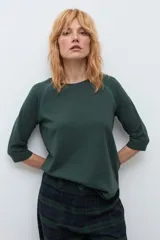 Remera de manga tres cuartos con diseño raglán y detalle de costura decorativa en los hombros. Presenta cuello redondo y un corte clásico.