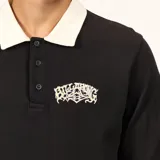 Remera tipo polo de manga larga en color negro, con cuello en contraste color crema y cierre frontal de tres botones. Presenta un pequeño estampado gráfico en el pecho.