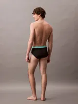 Pack de tres slips negros Calvin Klein con cintura elástica en colores lila, amarillo y celeste, con el logo de la marca.